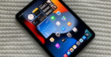 Kuvassa iPad mini, näyttö päällä. Näytössä näkyy laitteen kotivalikko.